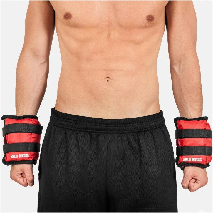 Polsiere zavorrate Gorilla Sports rosse e nere per allenamento fitness, indossate su braccia maschili