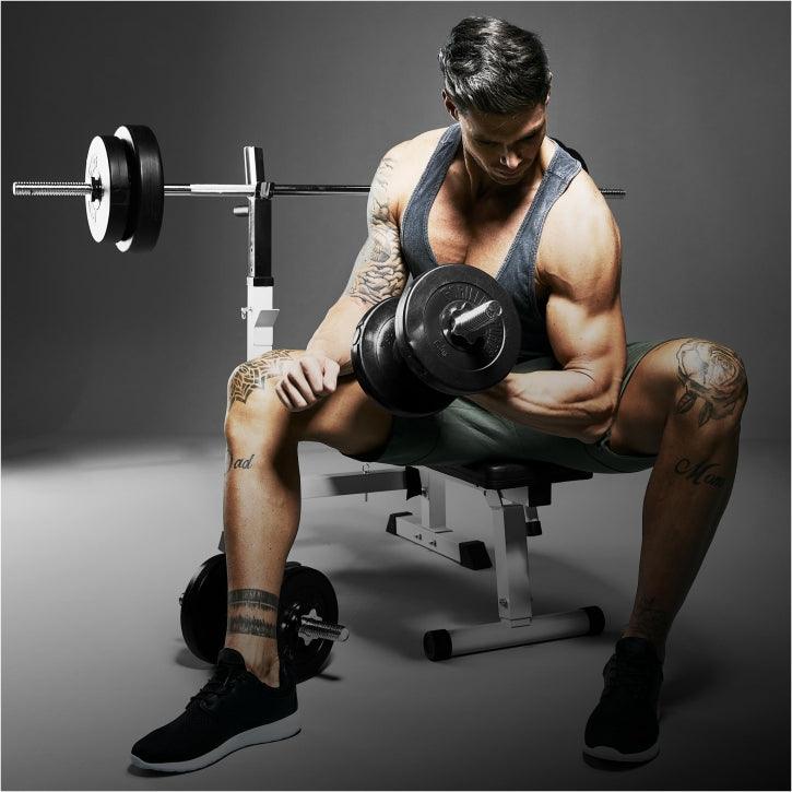 Uomo muscoloso con tatuaggi solleva manubrio in palestra, attrezzi Gorilla Sports, fitness