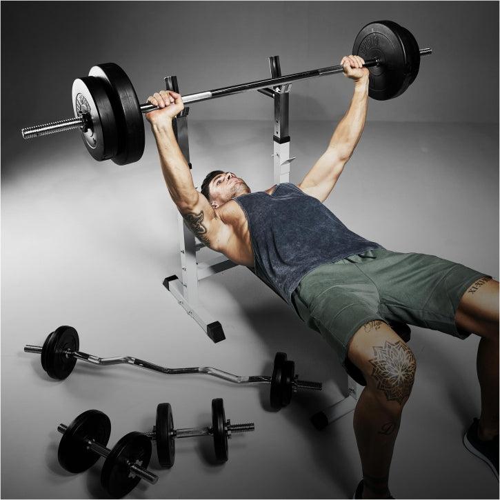 Uomo che si allena su panca piana Gorilla Sports con bilanciere e pesi, bodybuilding fitness