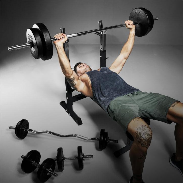 Uomo che solleva bilanciere su panca palestra Gorilla Sports, attrezzi fitness in vista