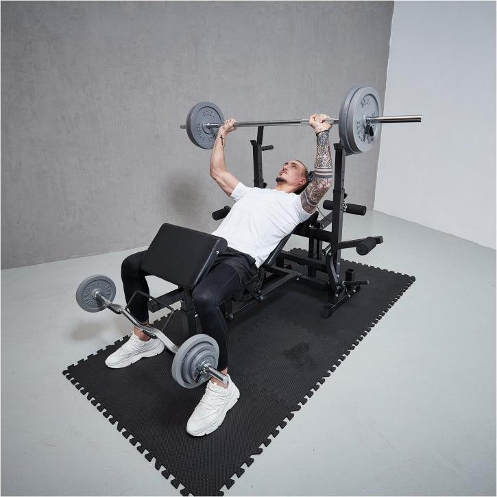 Uomo che si allena su panca multifunzione Gorilla Sports con bilancieri, palestra home fitness