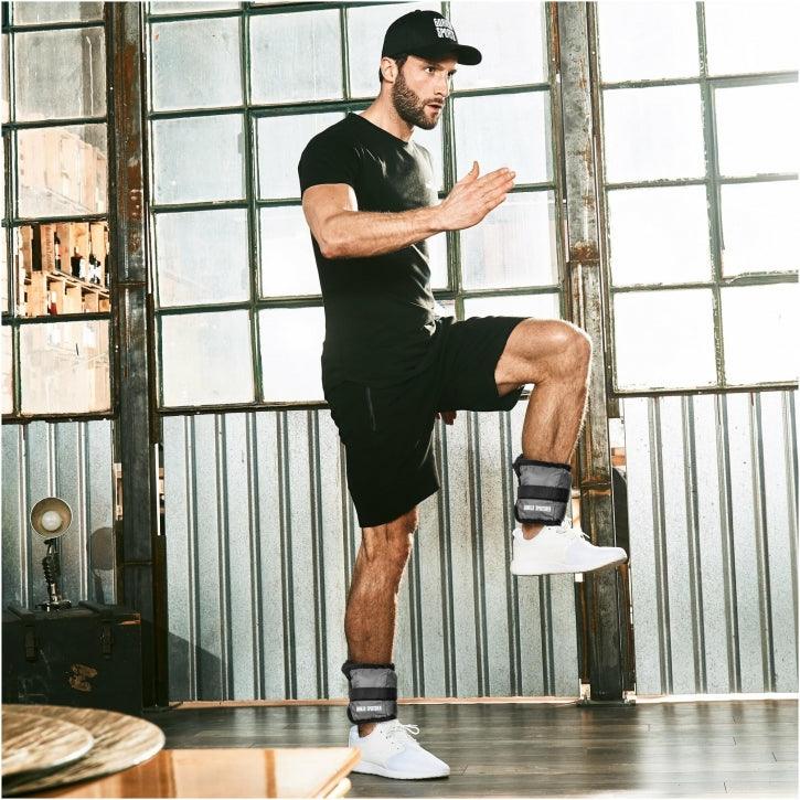 Uomo che indossa pesi cavigliere Gorilla Sports durante esercizio fitness in palestra