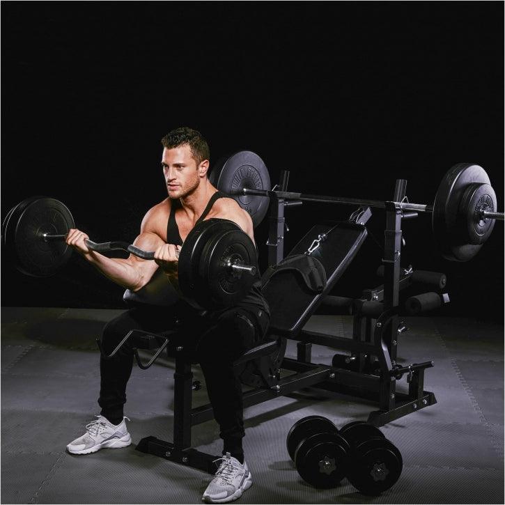 Uomo che esegue curl con bilanciere in palestra Gorilla Sports su panca fitness, bodybuilding